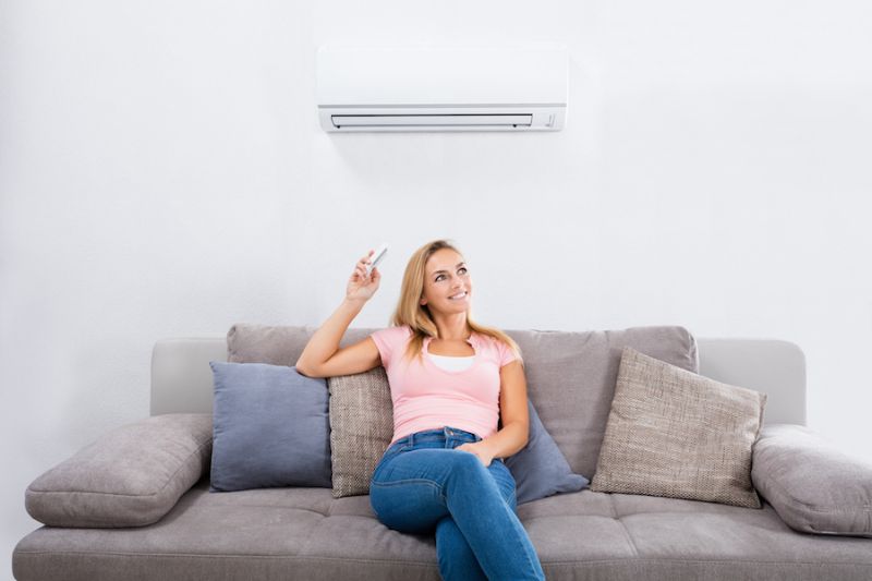 Image of person sitting below ductless system. Ductless AC's Improve Indoor Air Quality and Control Humidity.