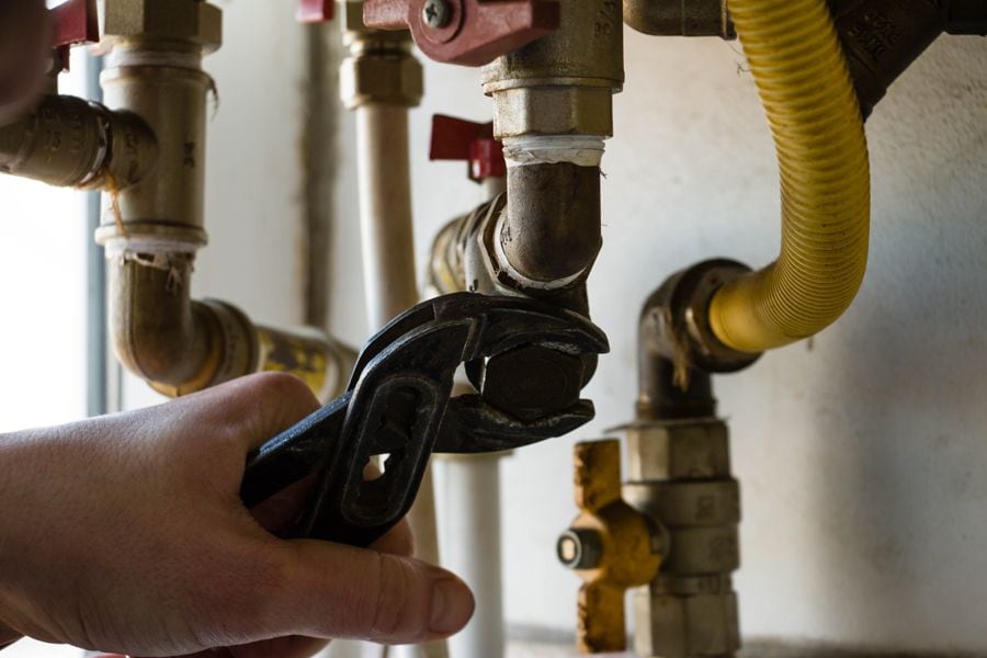 Everything You Need to Know About Boilers. Image depicts boiler pipes being tightened with wrench.