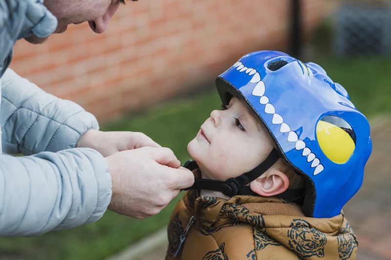 6 Ways Your Furnace Keeps You Safe. Photo of an adult tightening a helmet onto a child.