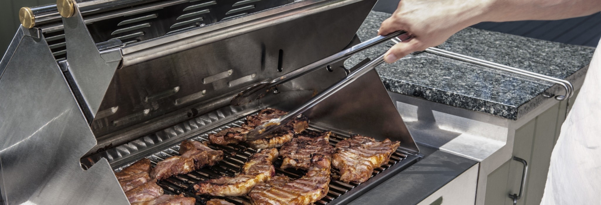 outdoor propane gas grill with man turning steaks.